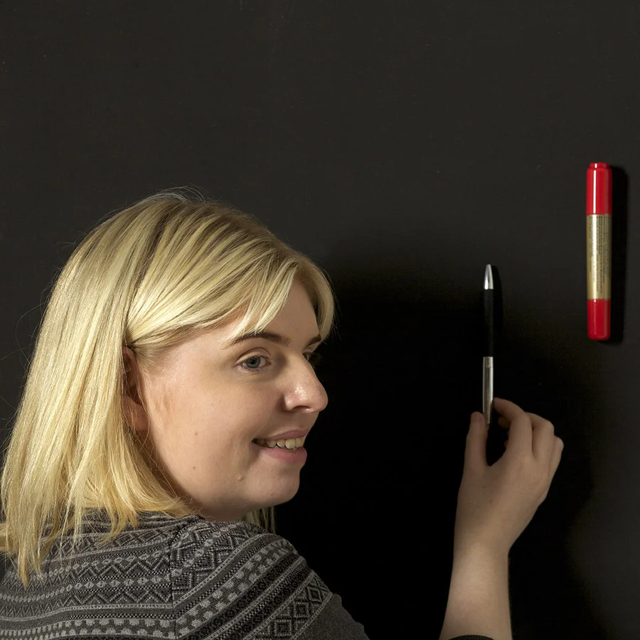Woman sticking up items on super magnetic paint for walls