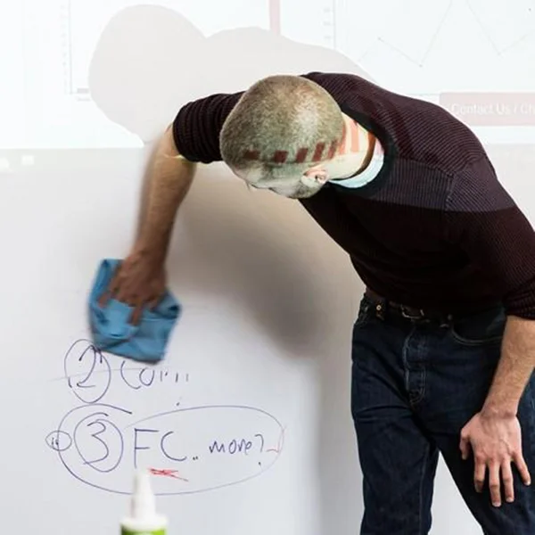 person at whiteboard cleaning it